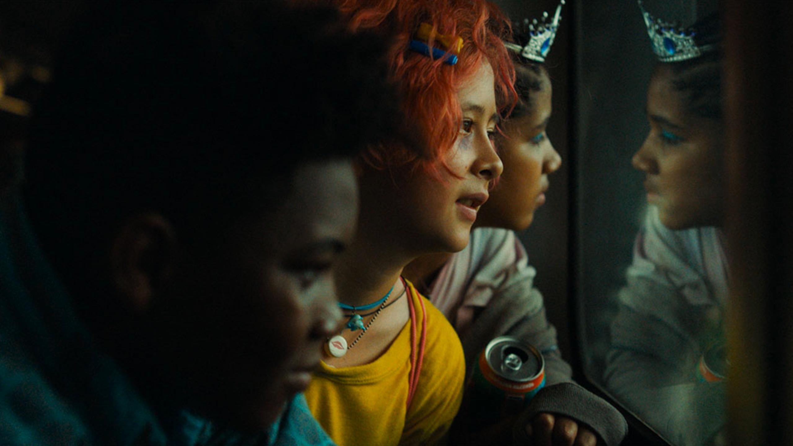 Three young people staring out a window with their reflection in it