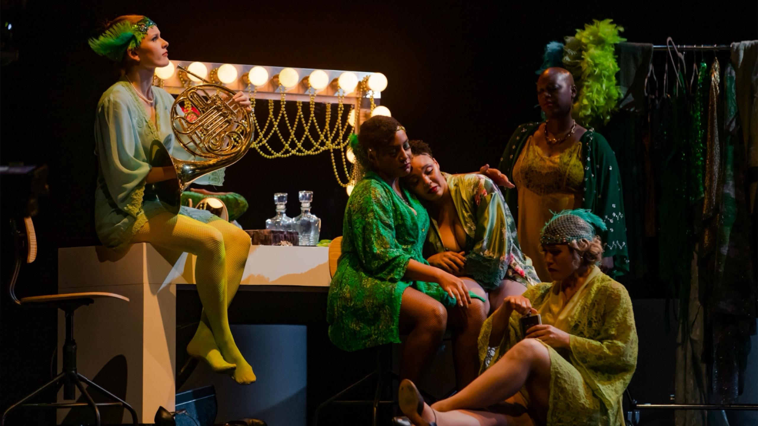 Image of the theatrical performance, five women sitting around a mirror that has lights around it all dressed in 1920s attire
