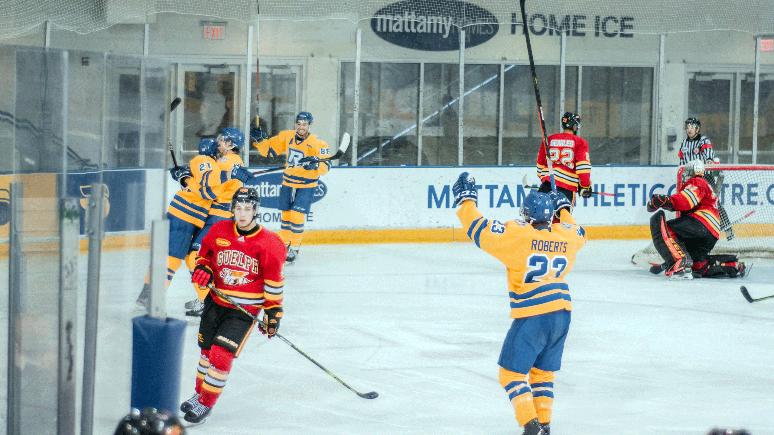 A group of hockey players in yellow jerseys celebrate a goal