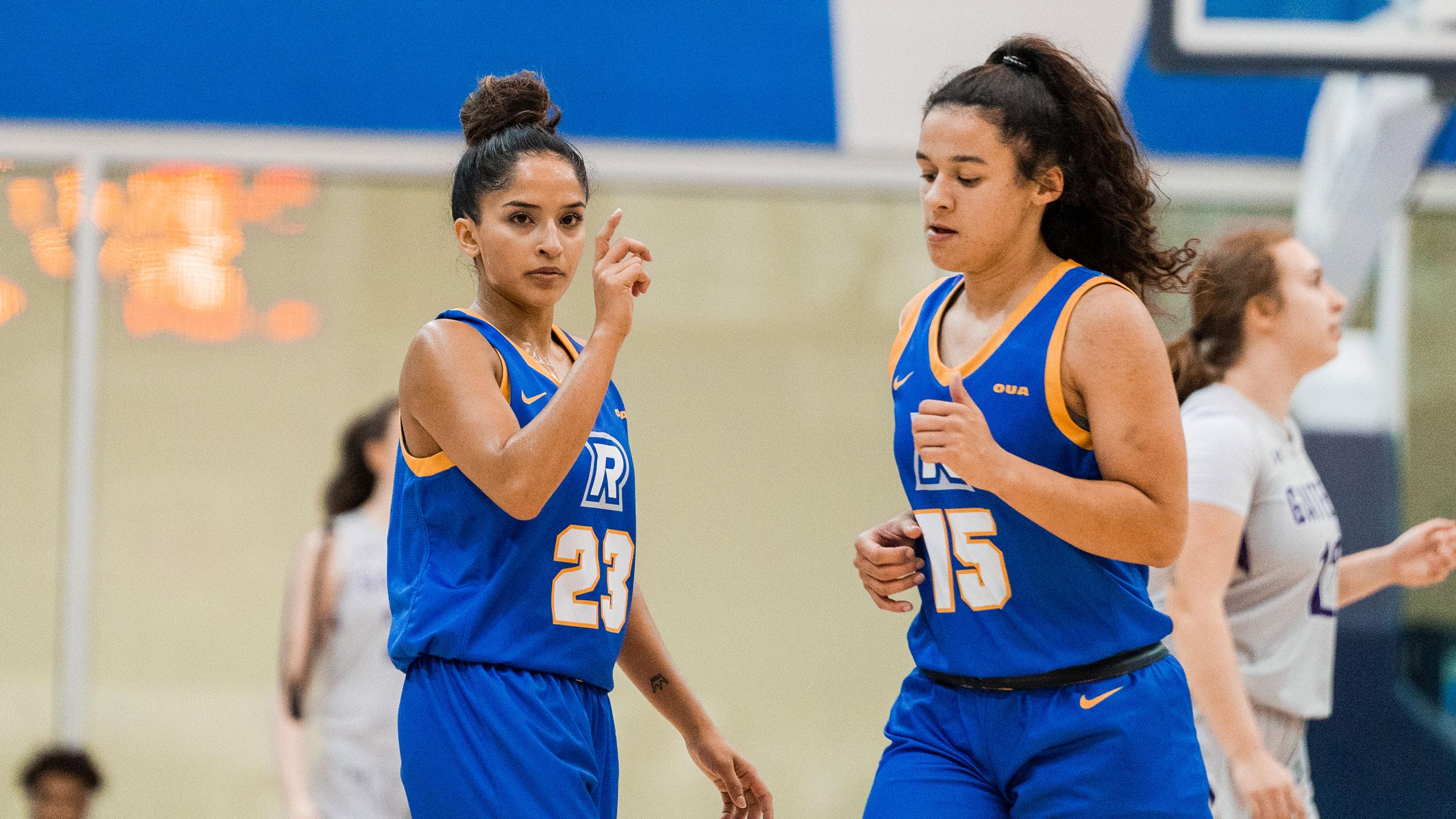 Two TMU women's basketball players in blue jerseys face the camera