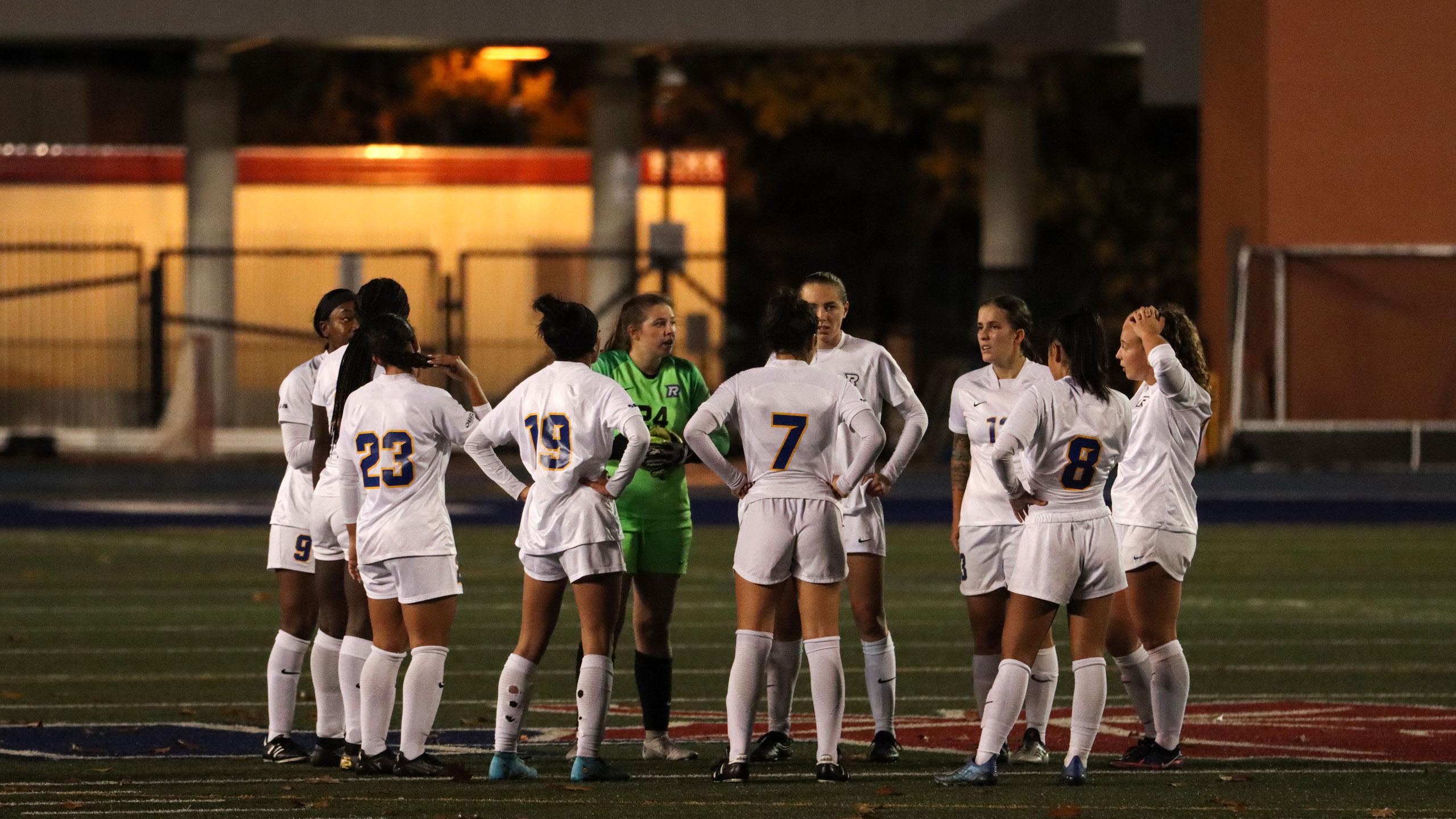 TMU women's soccer players in white jerseys huddle to talk