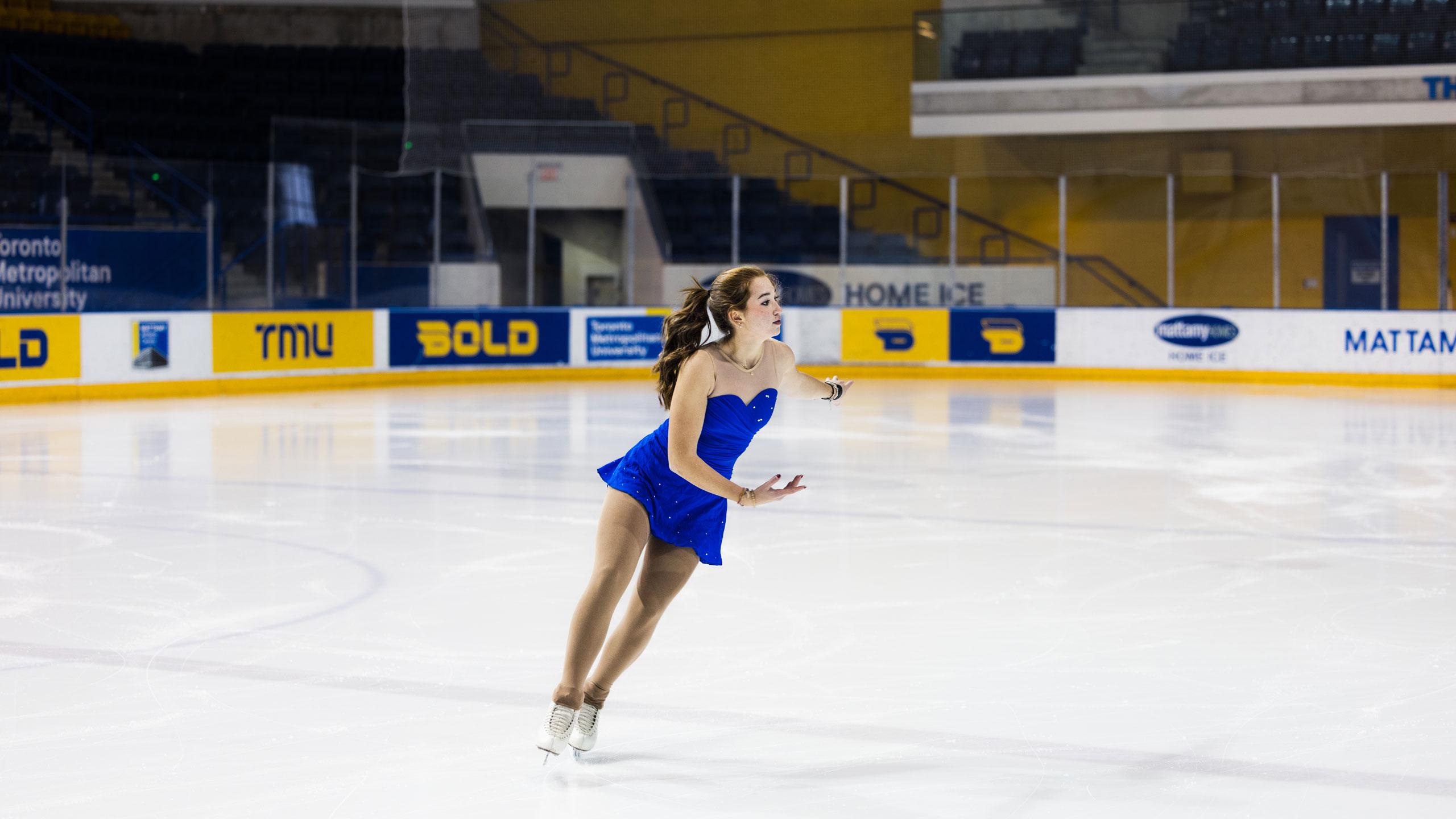 A TMU figure skating in a blue uniform skates at centre ice