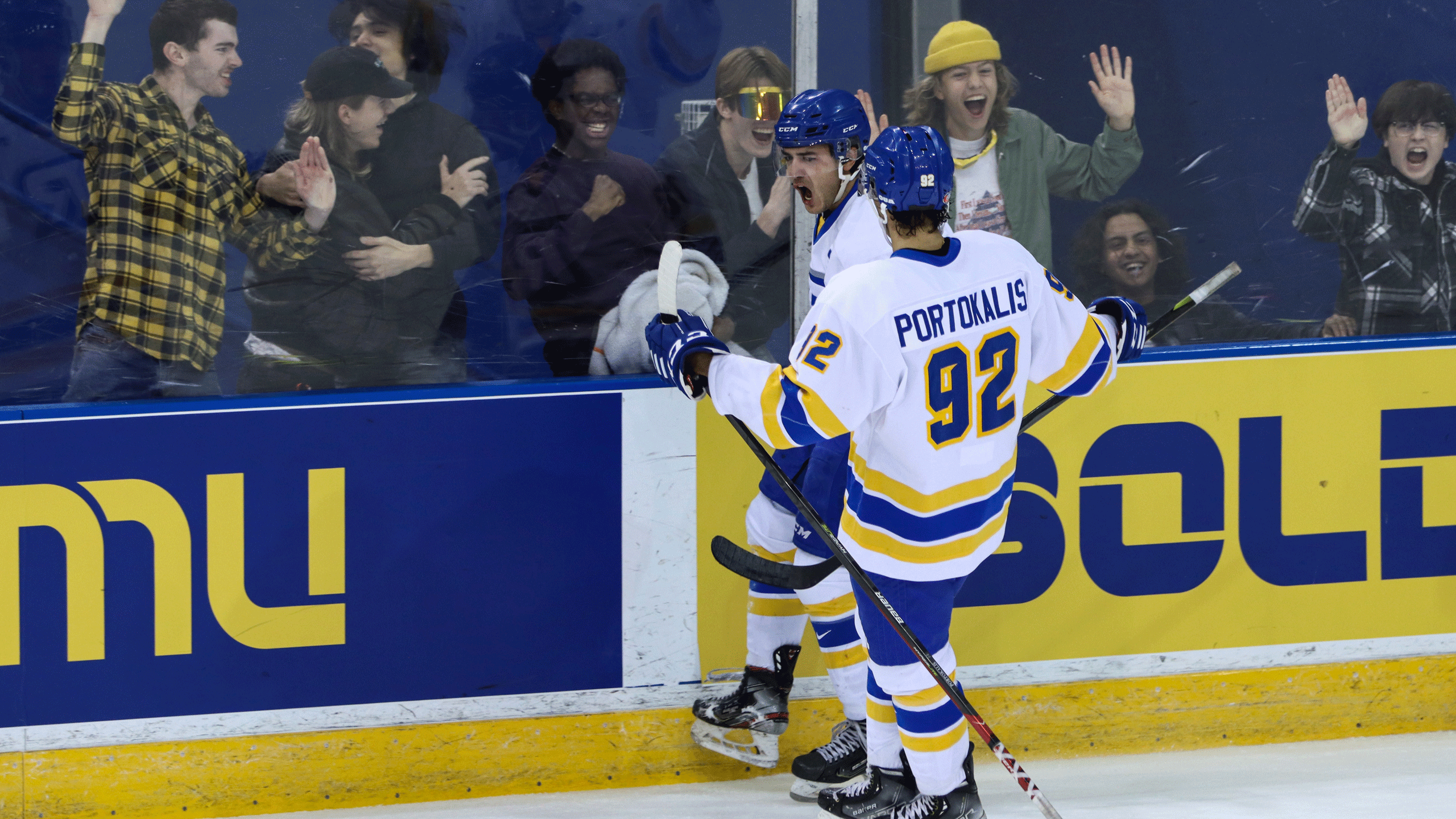 Two hockey players in white jerseys celebrate