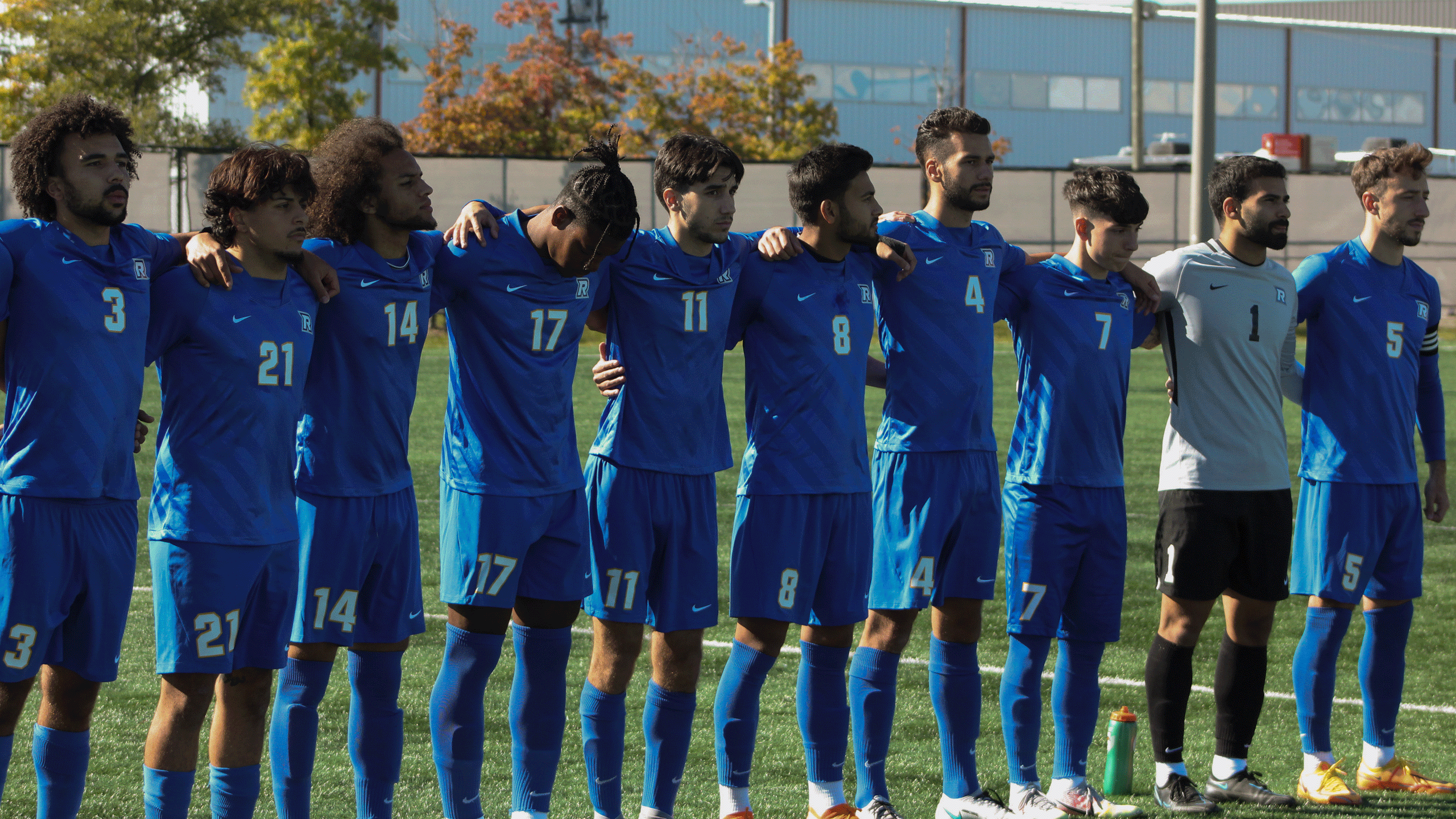A group of soccer players in blue jerseys huddle together