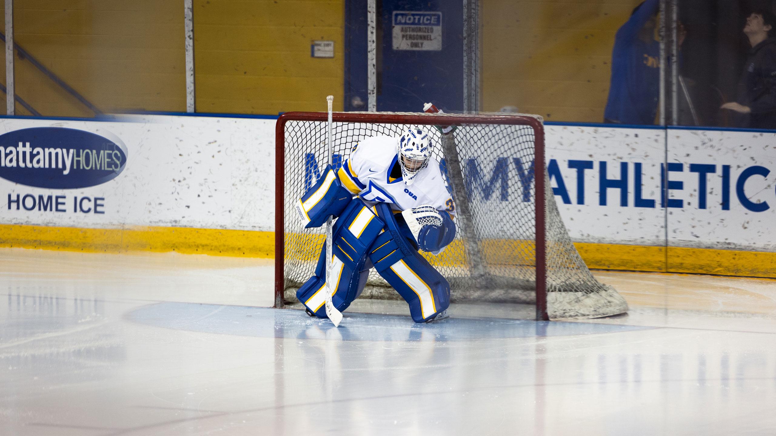 A TMU women's hockey player in a white jersey plays goalie