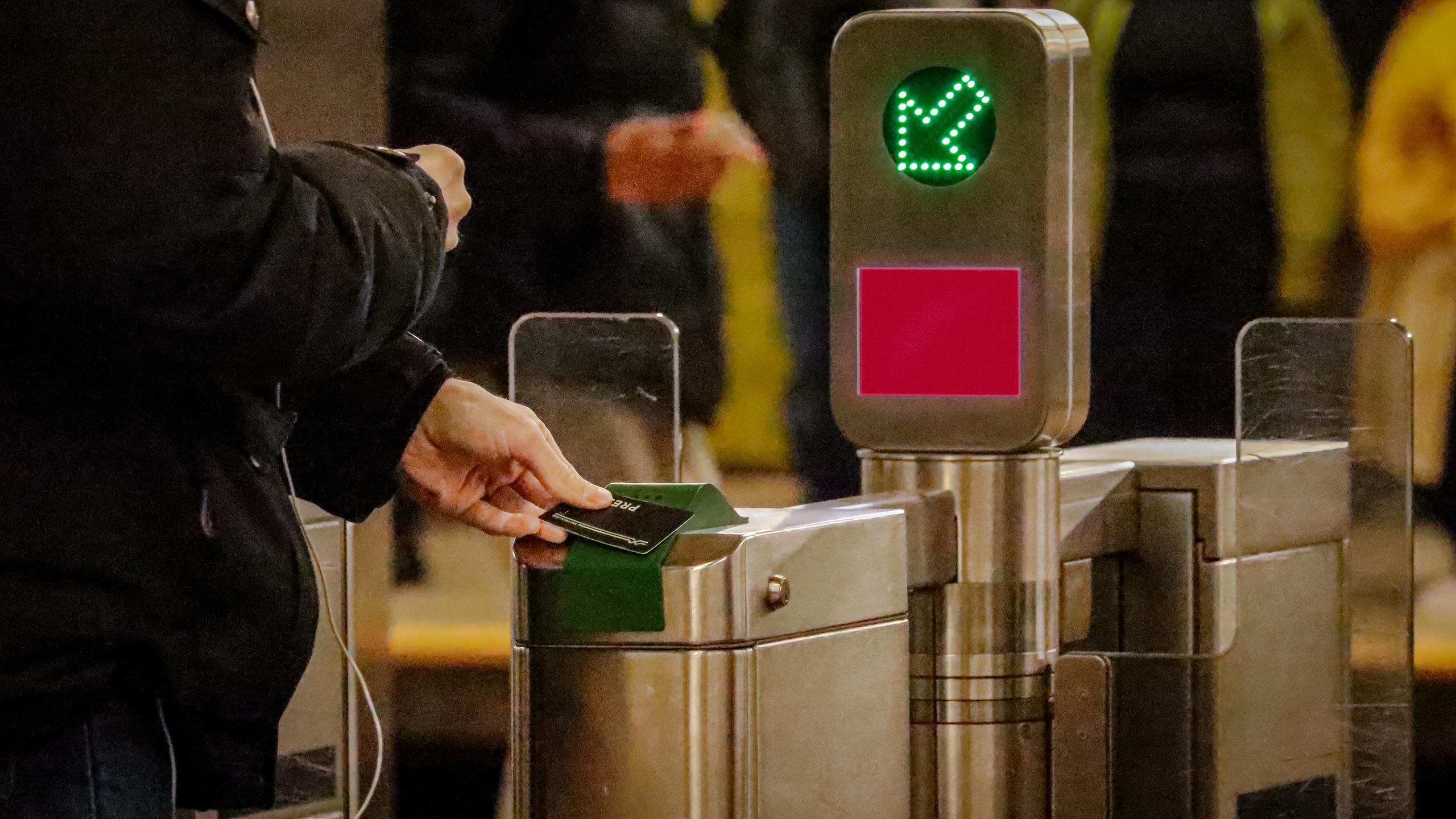 A person taps their presto card on the electronic reader but the screen is red, not allowing them to board the subway.