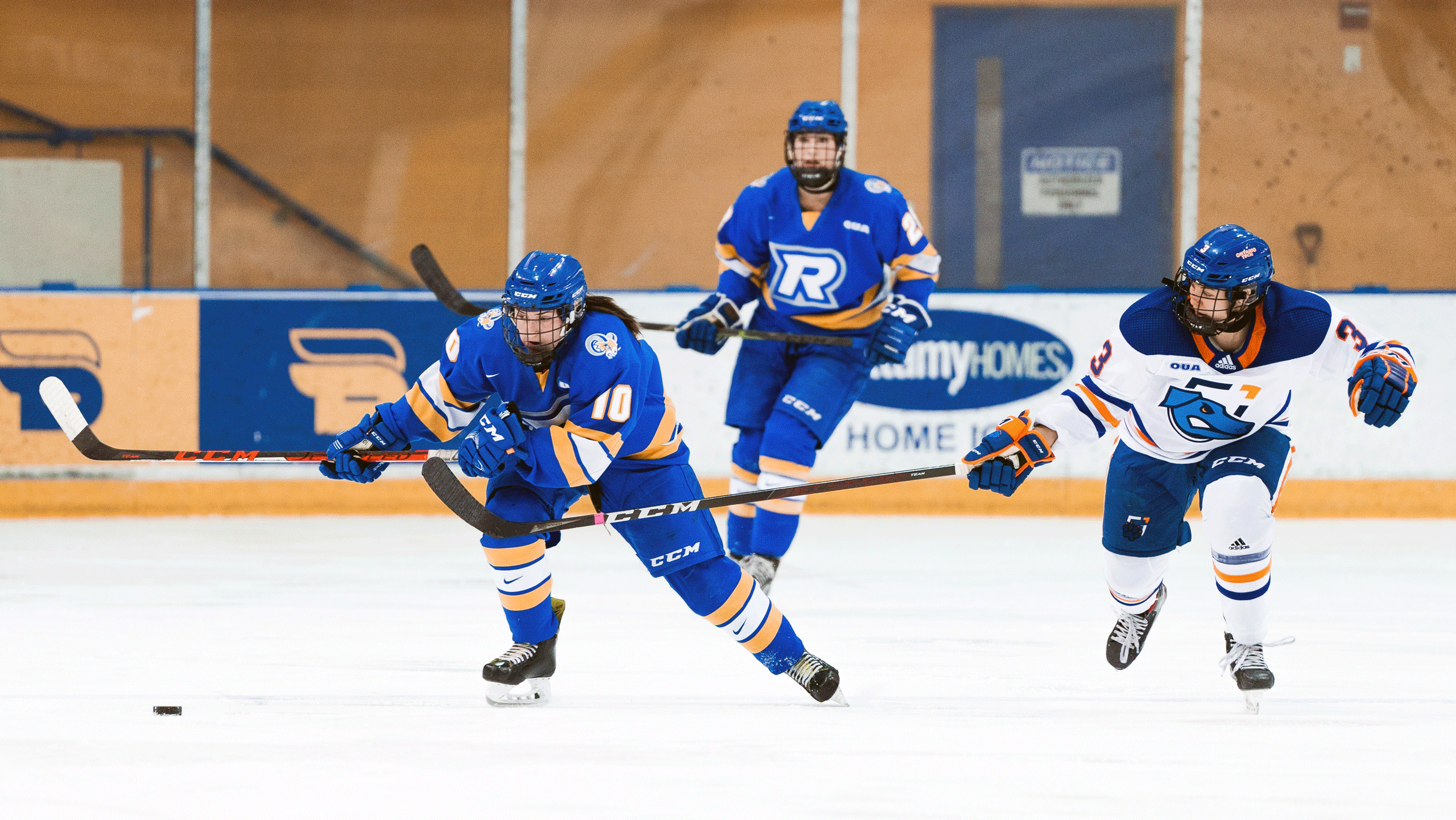 A hockey player in a blue jersey skates toward the puck