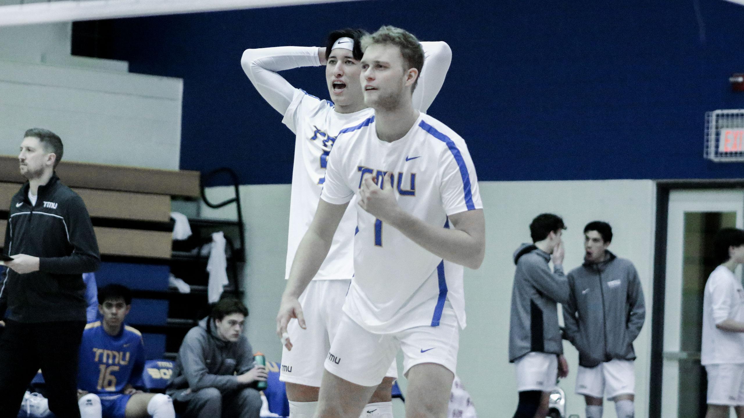 Two TMU men's volleyball players in white jerseys prepare for the next play