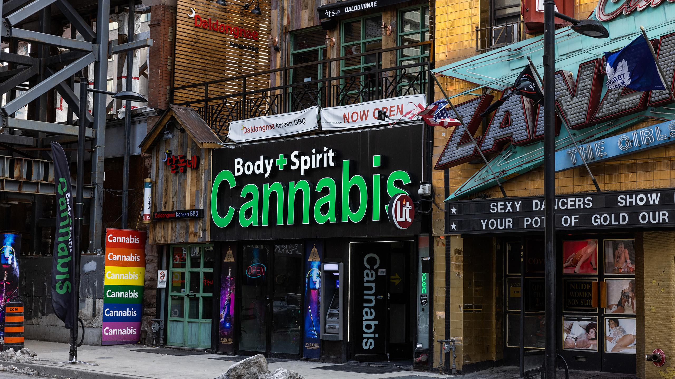 A green sign hanging on a black building reads "Body + Spirit Cannabis"
