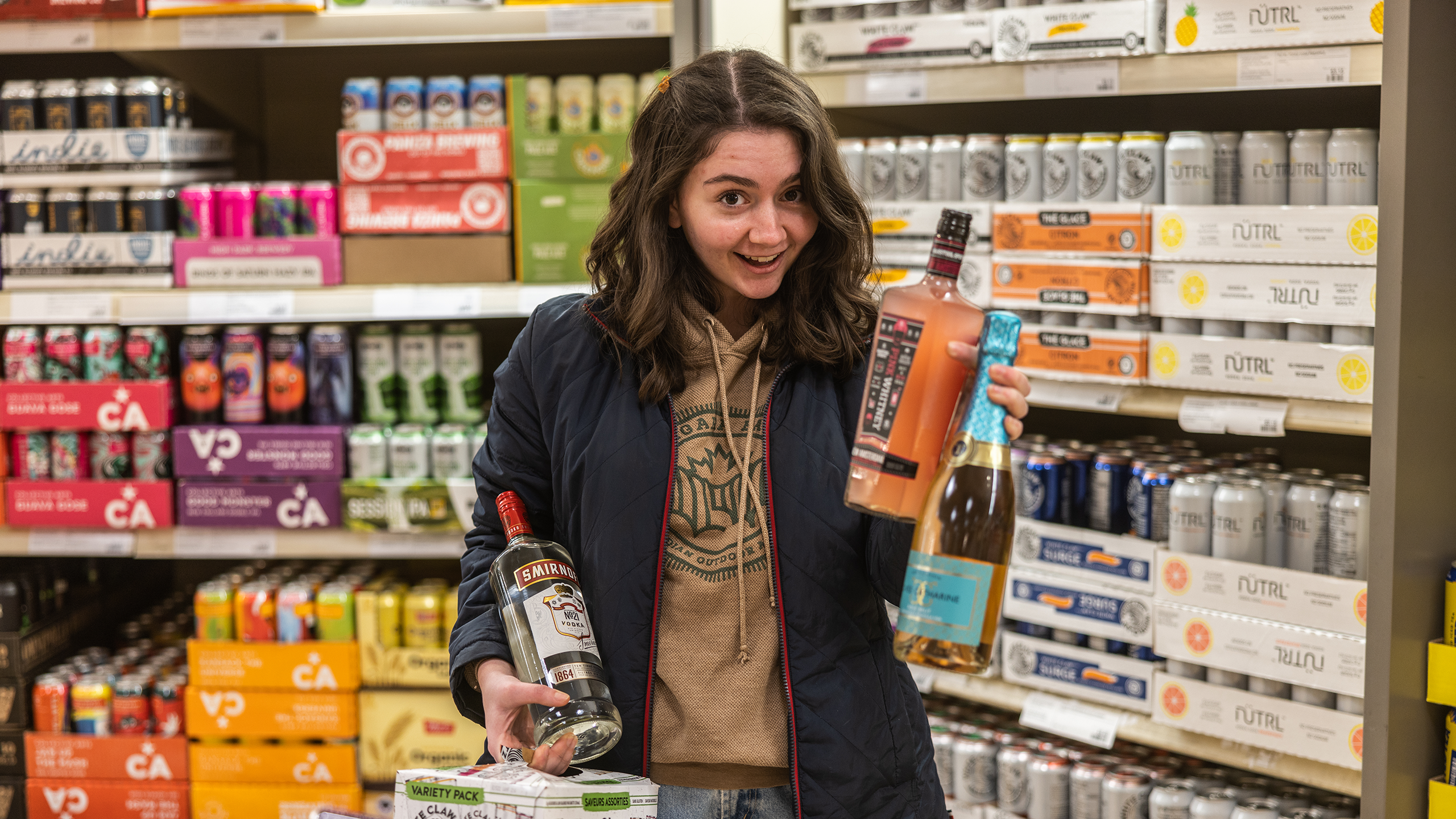 Vanessa holds various types of liquor with a smile