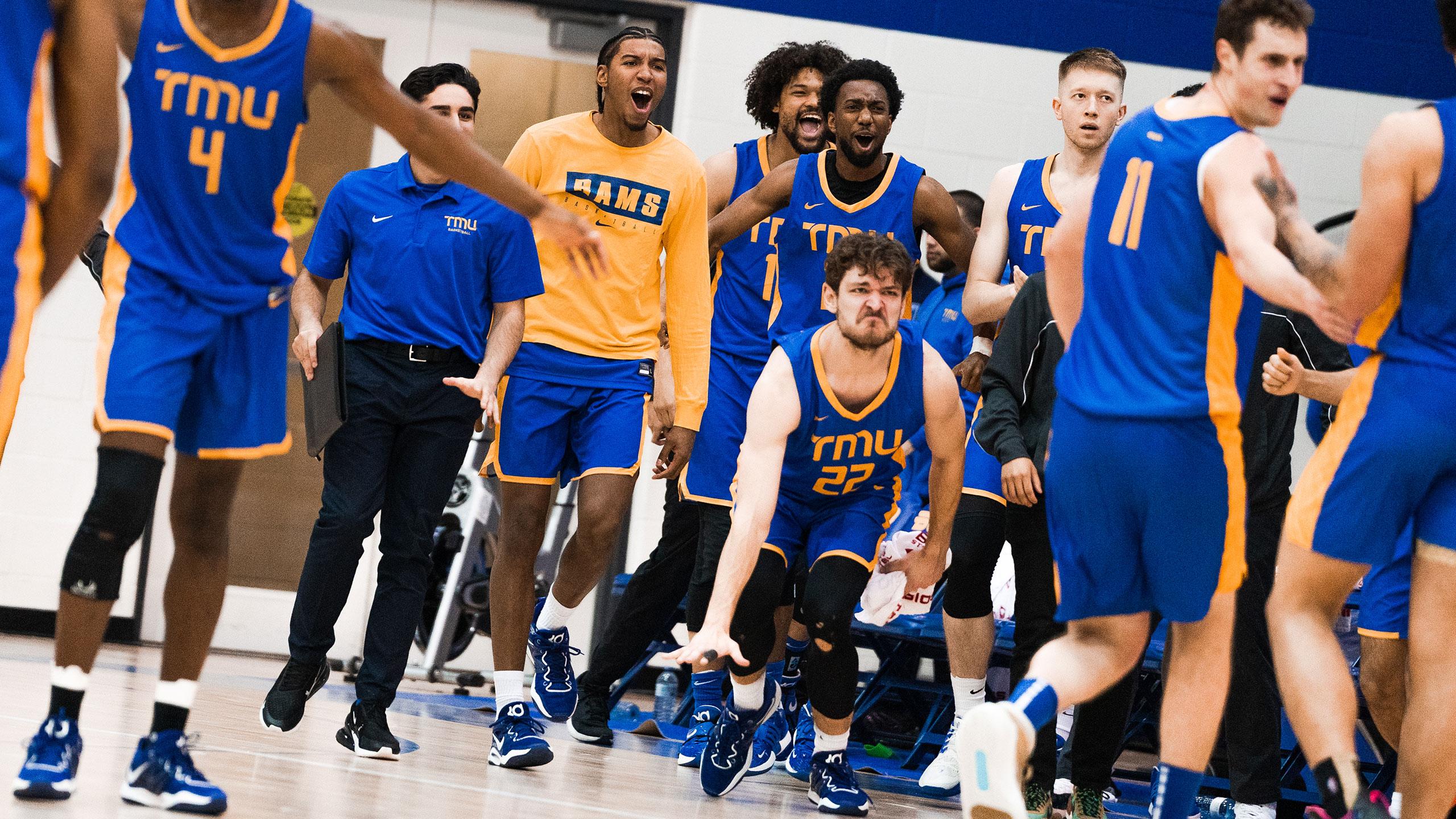 The TMU men's basketball team in blue jerseys celebrate after a big bucket