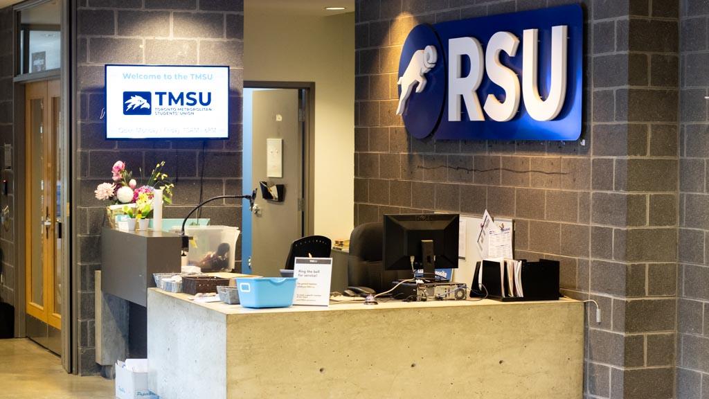 The TMSU desk in the SCC. A blue sign reads "RSU" and a white TV screen reads" TMSU"