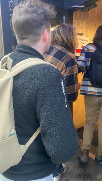 Three men's backs, one of which has bird poop on his right arm