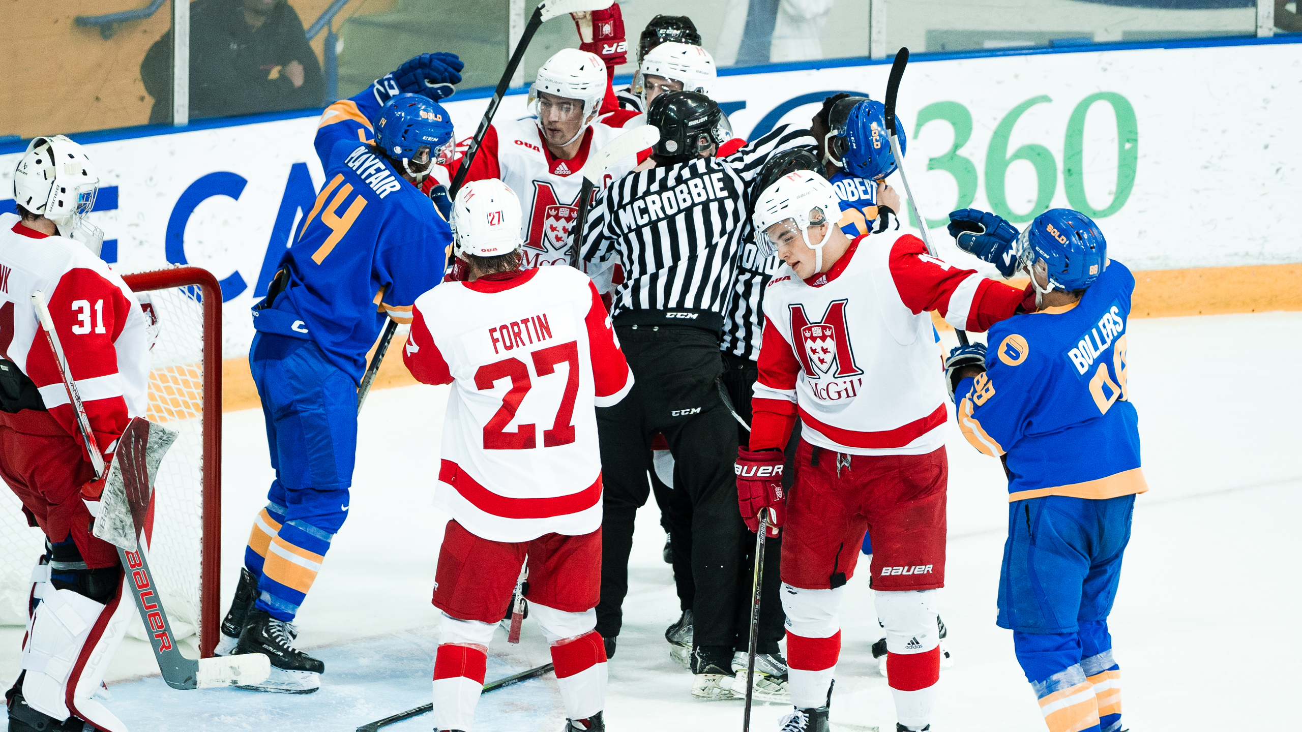 Several TMU Bold men's hockey players engage in a scrum with McGill Redbirds players