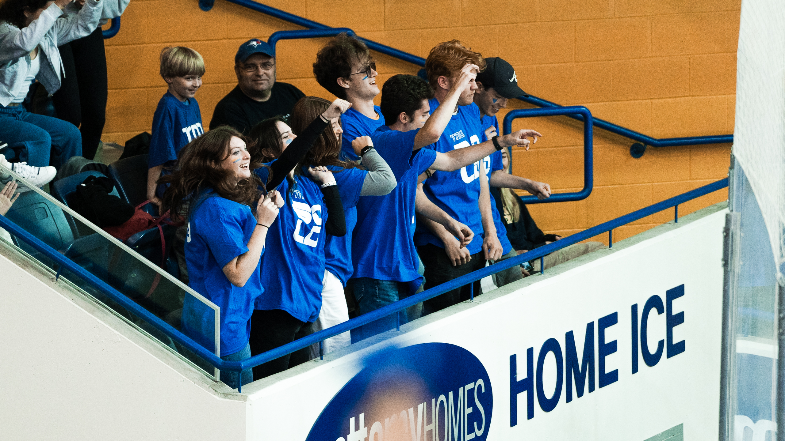 A group of TMU students cheer on the TMU Bold men's hockey team