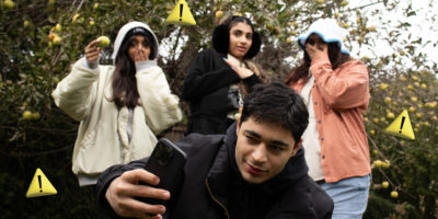 Man taking a selfie with people in the background looking surprised