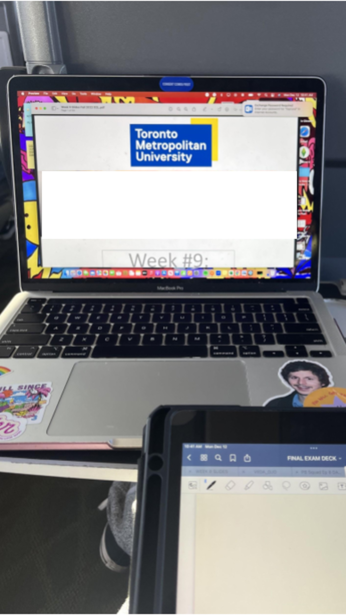 Tablet in the foreground with a laptop sitting on the table with university's website in the background