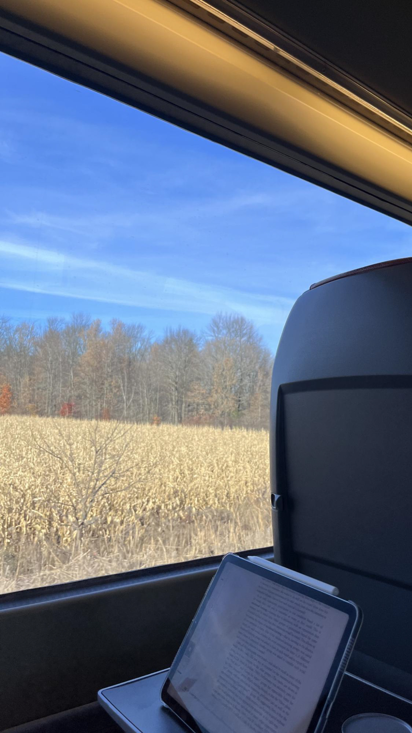 Work tablet on train seat table with a view of farm field