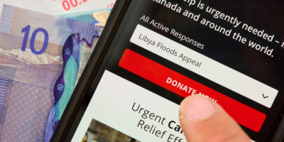 Person uses phone with donate button for Libya floods fundraiser
