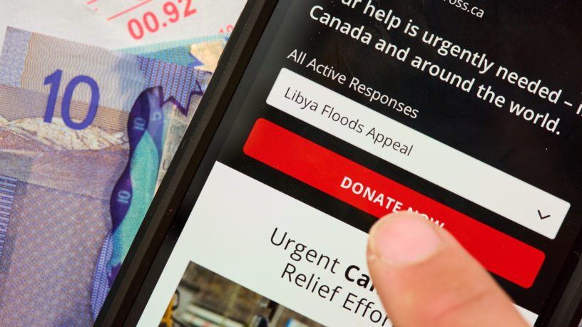 Person uses phone with donate button for Libya floods fundraiser