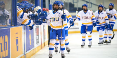 TMU women's hockey team flies by their bench and fist bumps their team after a goal