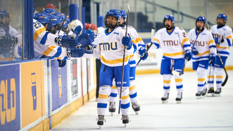TMU women's hockey team flies by their bench and fist bumps their team after a goal