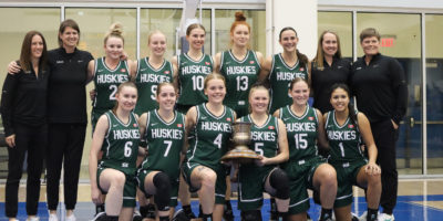 The Saskatchewan Huskies women's basketball pose while holding the Darcel Wright Memorial Classic trophy