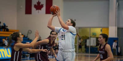 TMU women's basketball player Corynn Parker shoots the ball as several McMaster Marauders players look at her