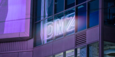 Glowing sign on side of building reads "DMZ"