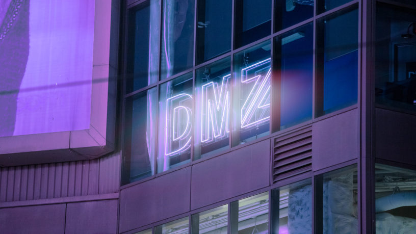 Glowing sign on side of building reads "DMZ"