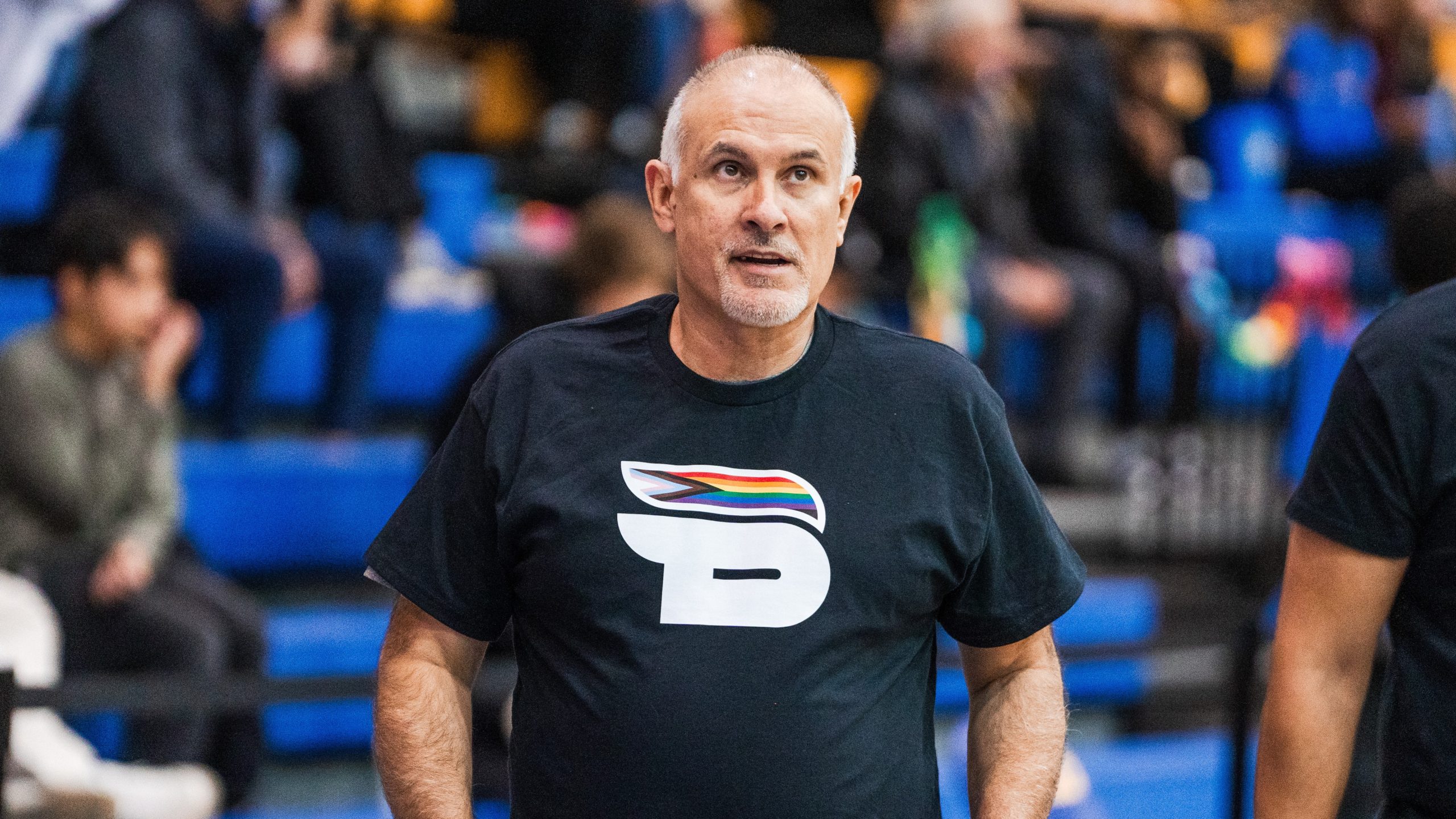 TMU men's basketball head coach David DeAveiro stands on the court wearing the Bold Pride shirt