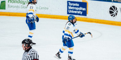 TMU women's hockey players Emily Baxter and Megan Breen look skywards while skating