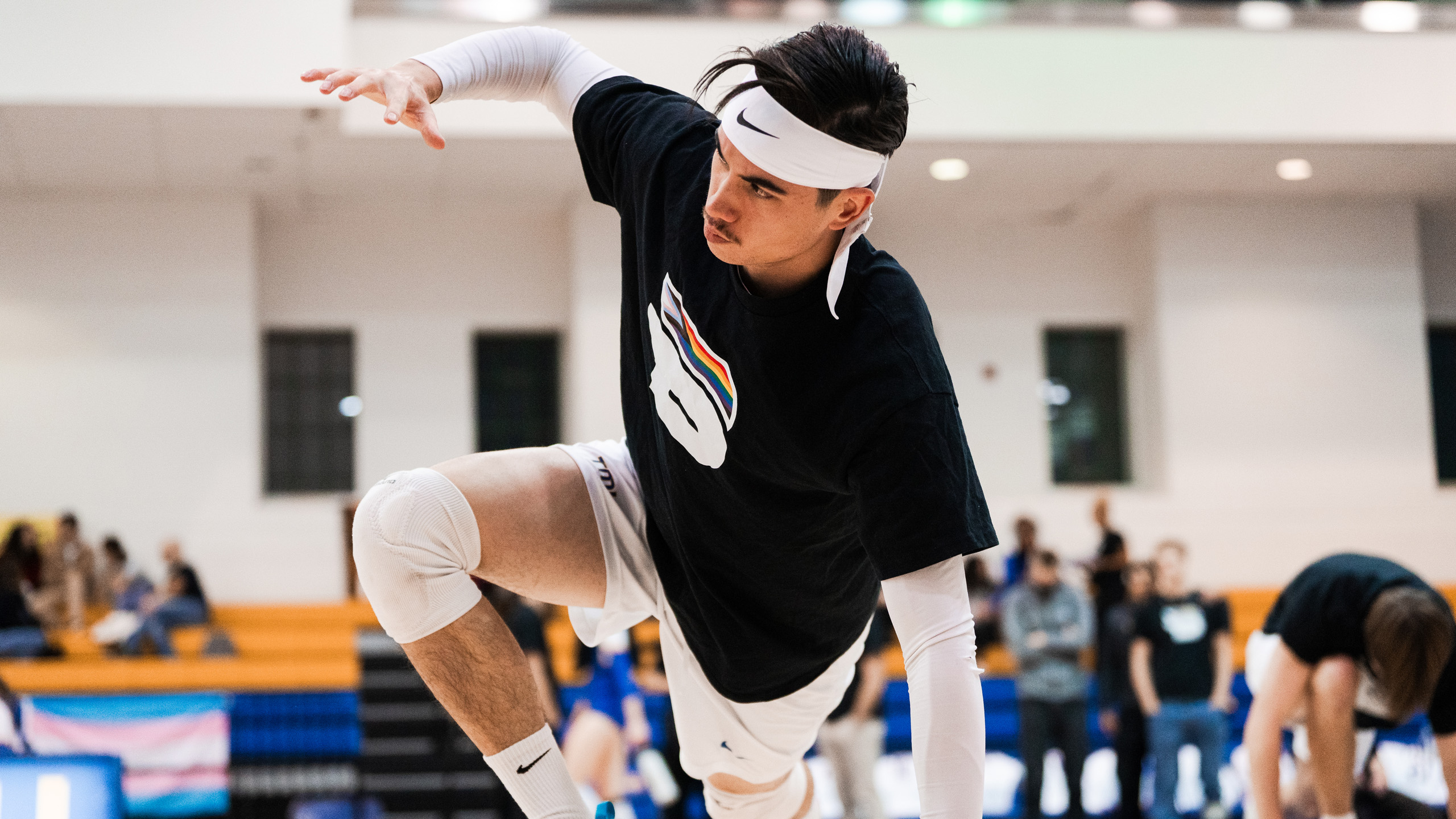 TMU men's volleyball player Lucas Yang stretches during warmups wearing the Bold Pride shirt