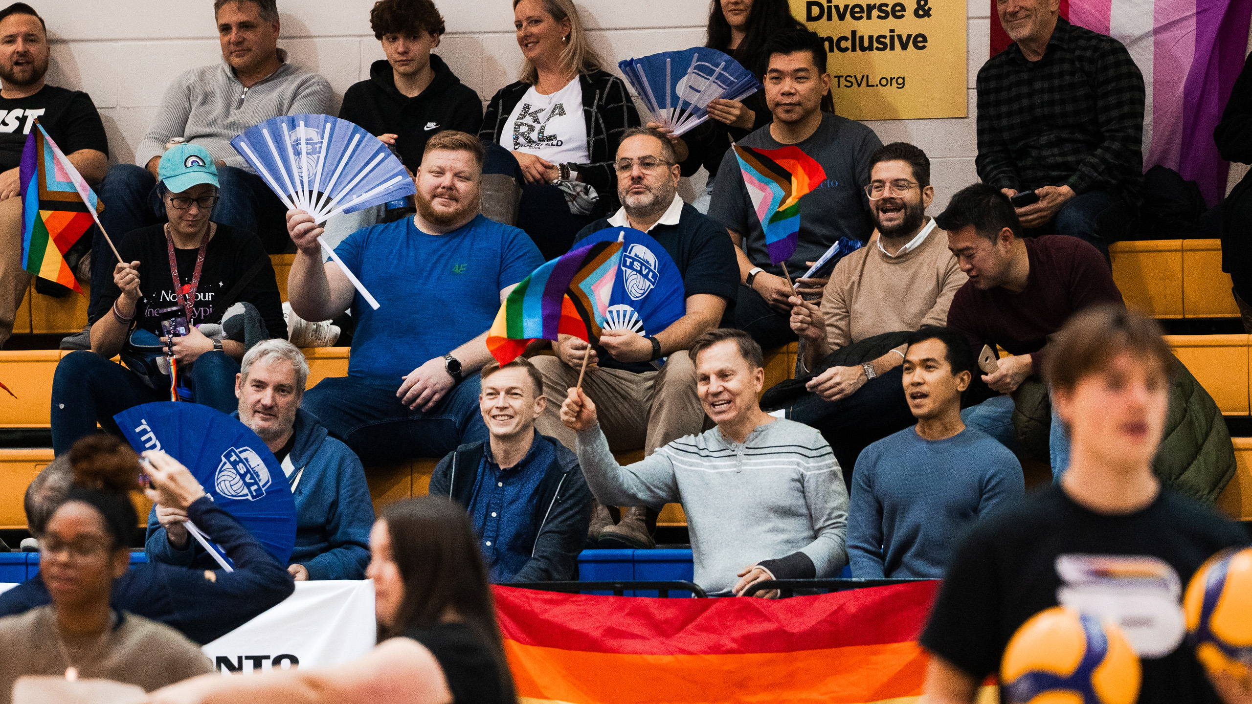 People in the crowd of the MAC wave Pride flags and folding fans