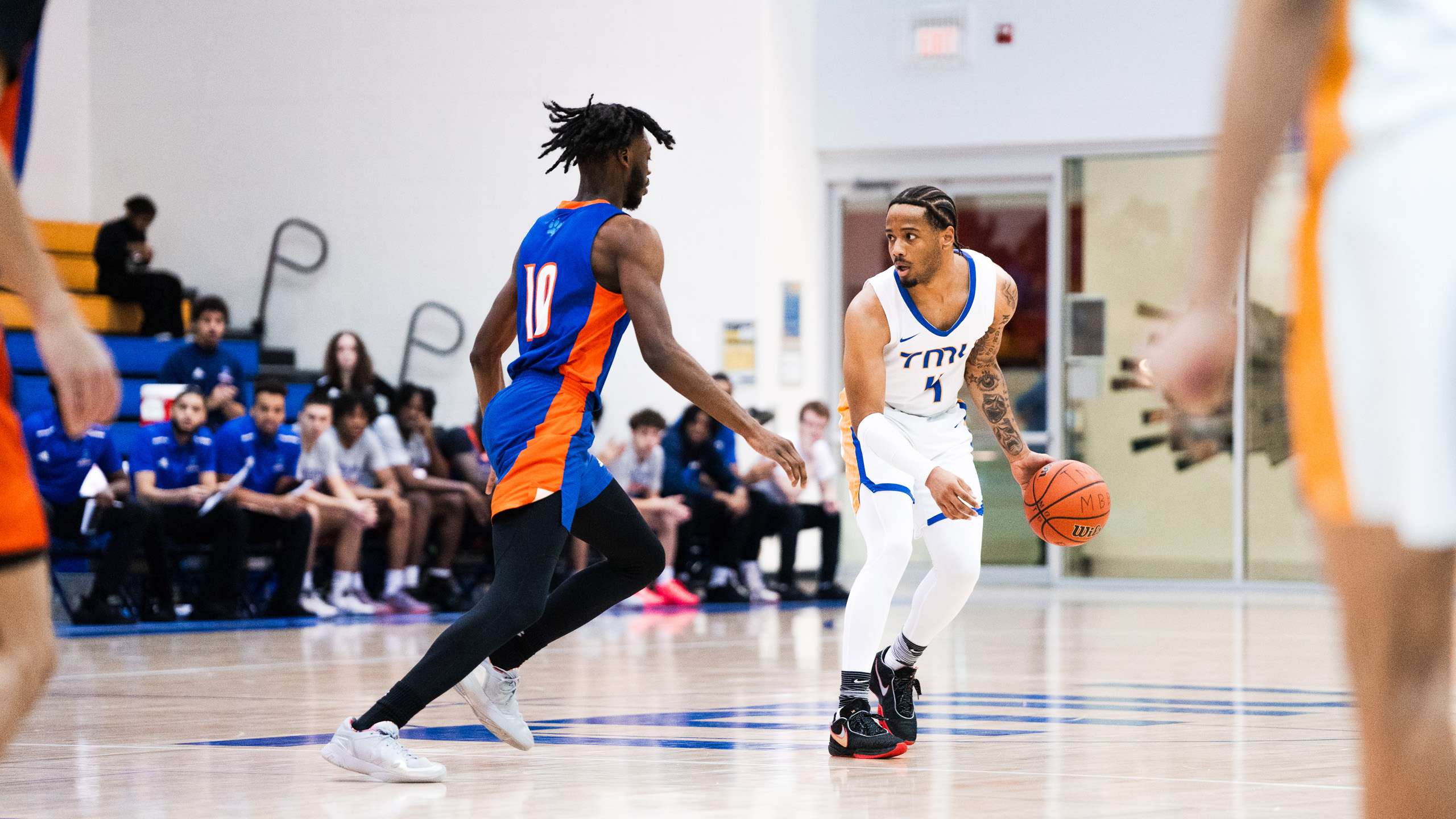TMU men's basketball player Cameron Ramage dribbles the ball while being guarded by a Ridgebacks player