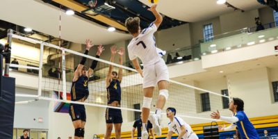 TMU men's volleyball player Ben Davey prepares to hit the ball as two Windsor Lancers player jump to block the ball
