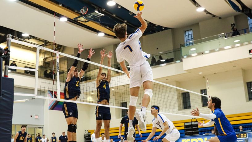 TMU men's volleyball player Ben Davey prepares to hit the ball as two Windsor Lancers player jump to block the ball
