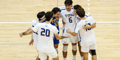 Players of the TMU men's volleyball team huddle in celebration of a win