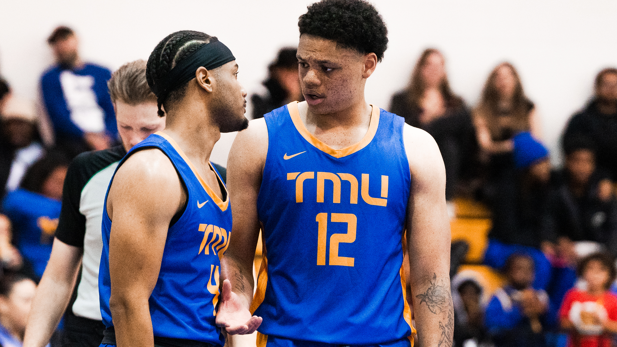 TMU Bold men's basketball players Aaron Rhooms and Cameron Ramage talk on the court