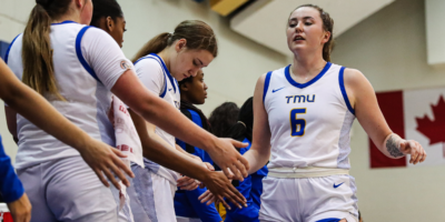 Members of the TMU Bold women's basketball team high five Haley Fedick as she comes out of the game