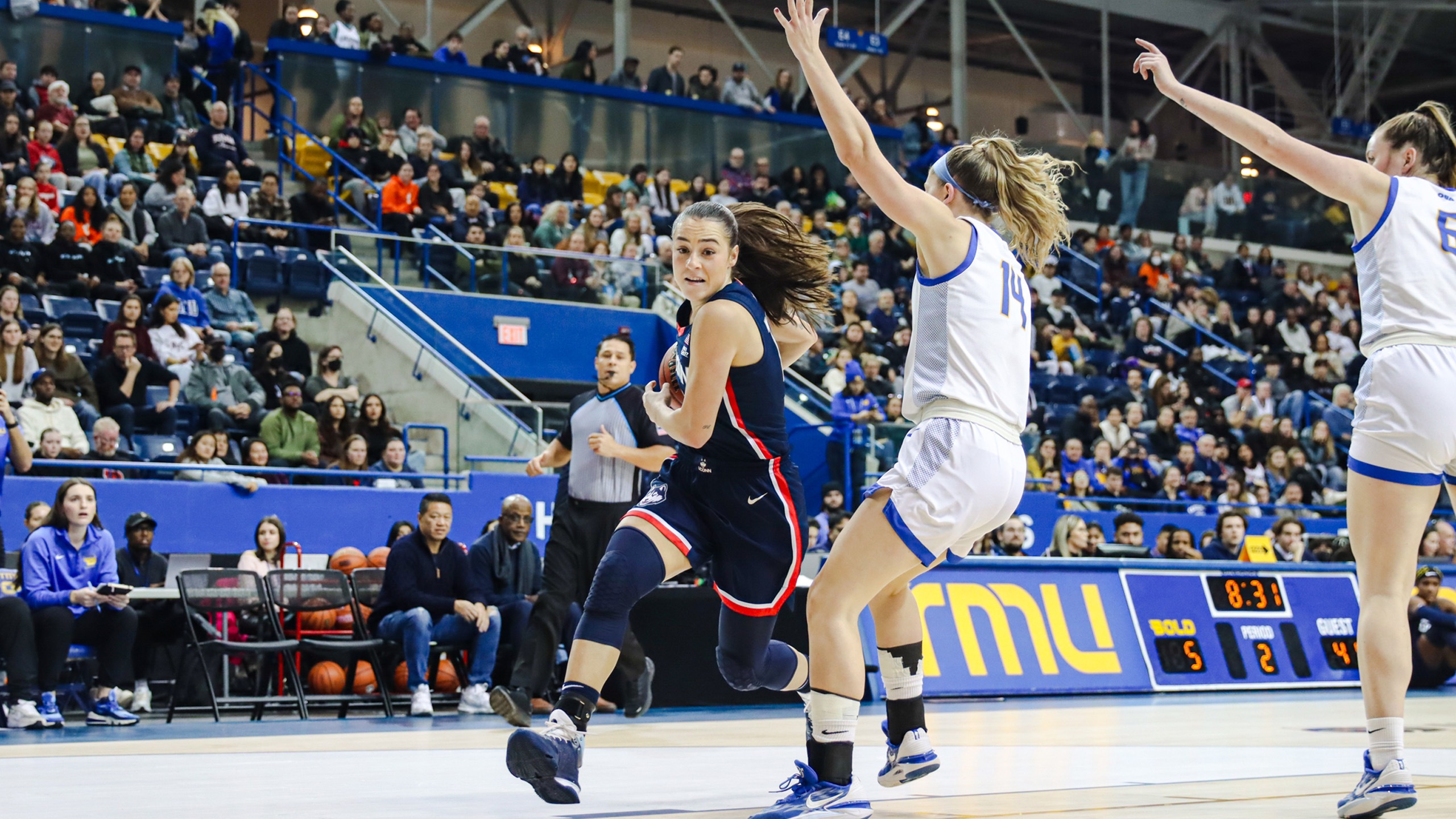 UConn Huskies women's basketball player Nika Muhl drives past TMU women's basketball player Kaillie Hall