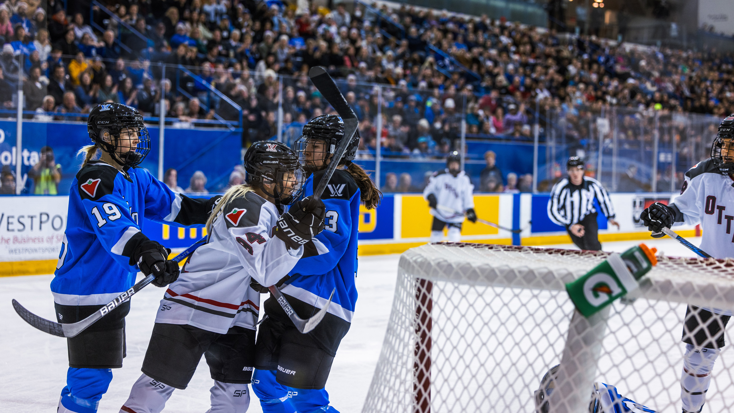 PWHL Toronto players Jocelyne Larocque and Rebecca Leslie push PWHL Ottawa player Fanni Garât-Gasparics away from their goal