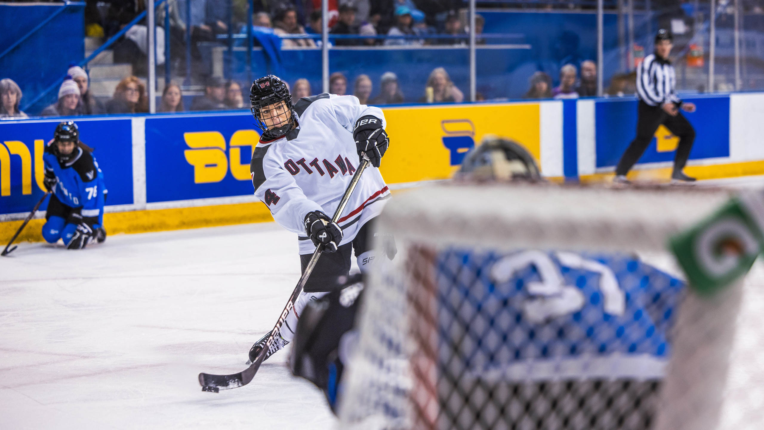 A PWHL Ottawa player shots the puck towards the Toronto net