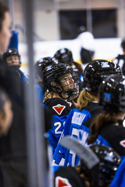 A PWHL Toronto player looks to the ice from the bench