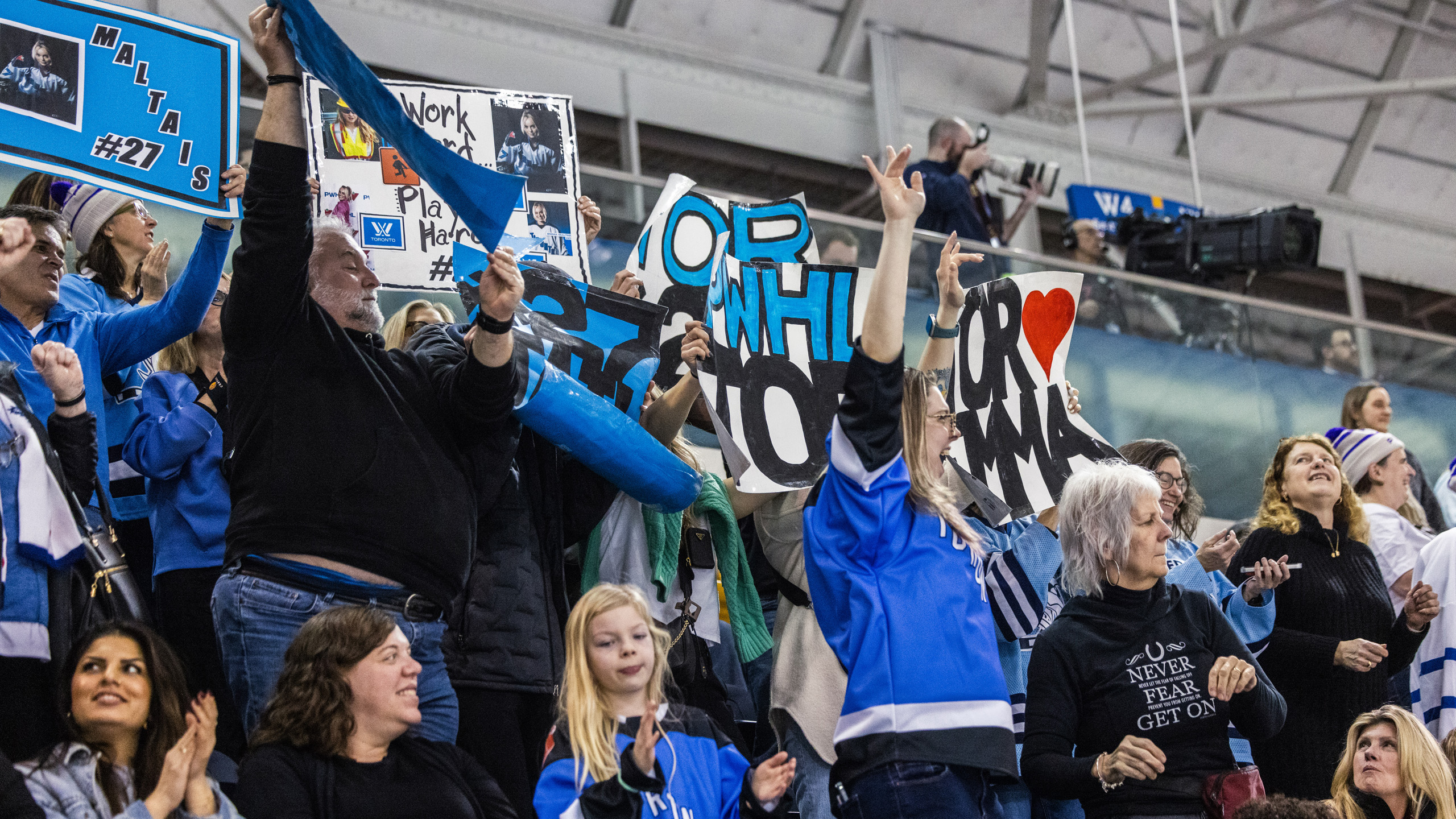 PWHL Toronto fans hold up signs in the stands