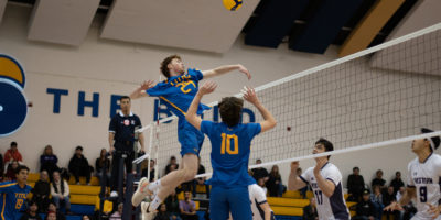 TMU men's volleyball player Liam Cobb spikes the ball over the net against the Western Mustangs