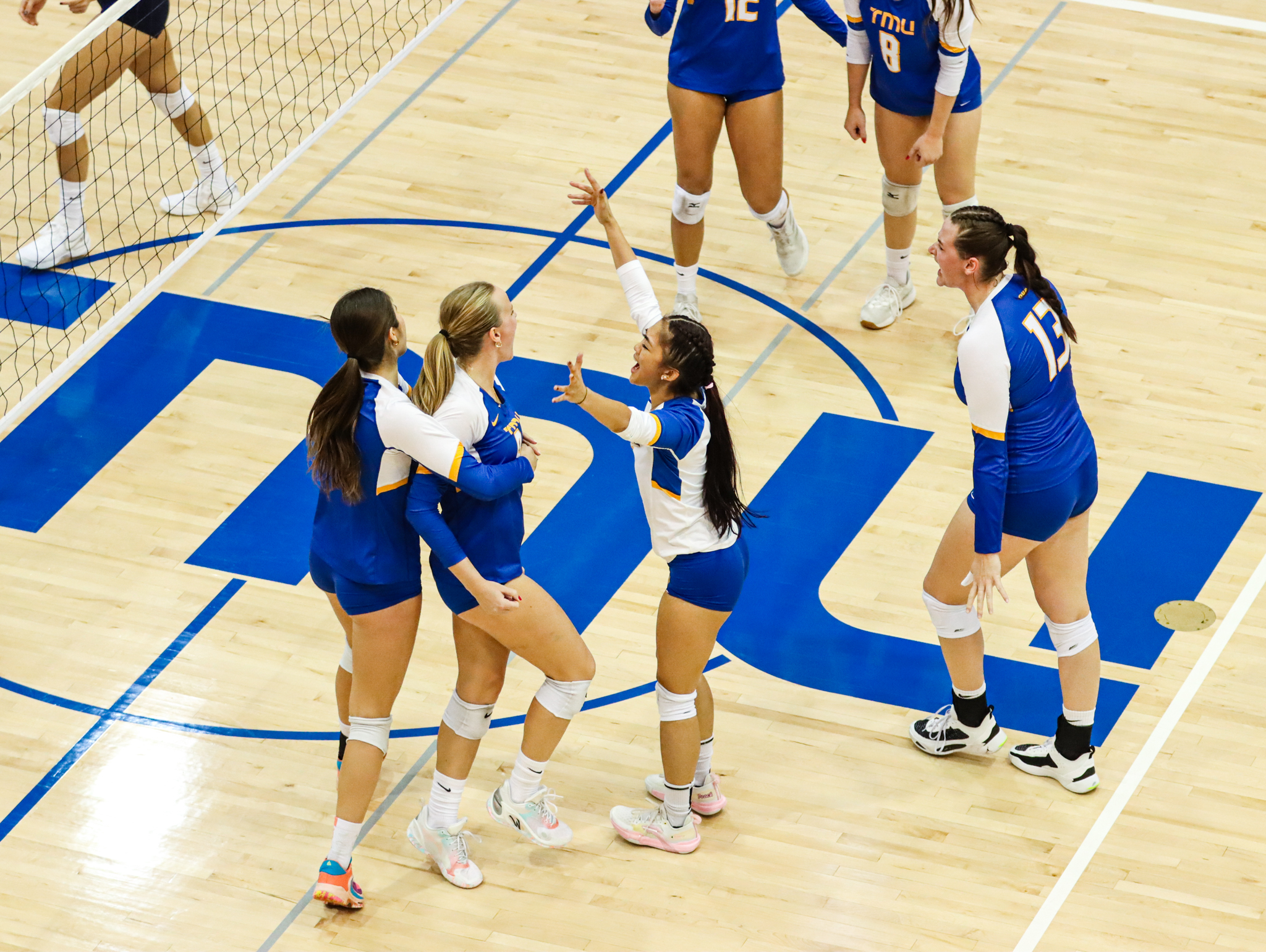 The women's volleyball team gather together to celebrate a point