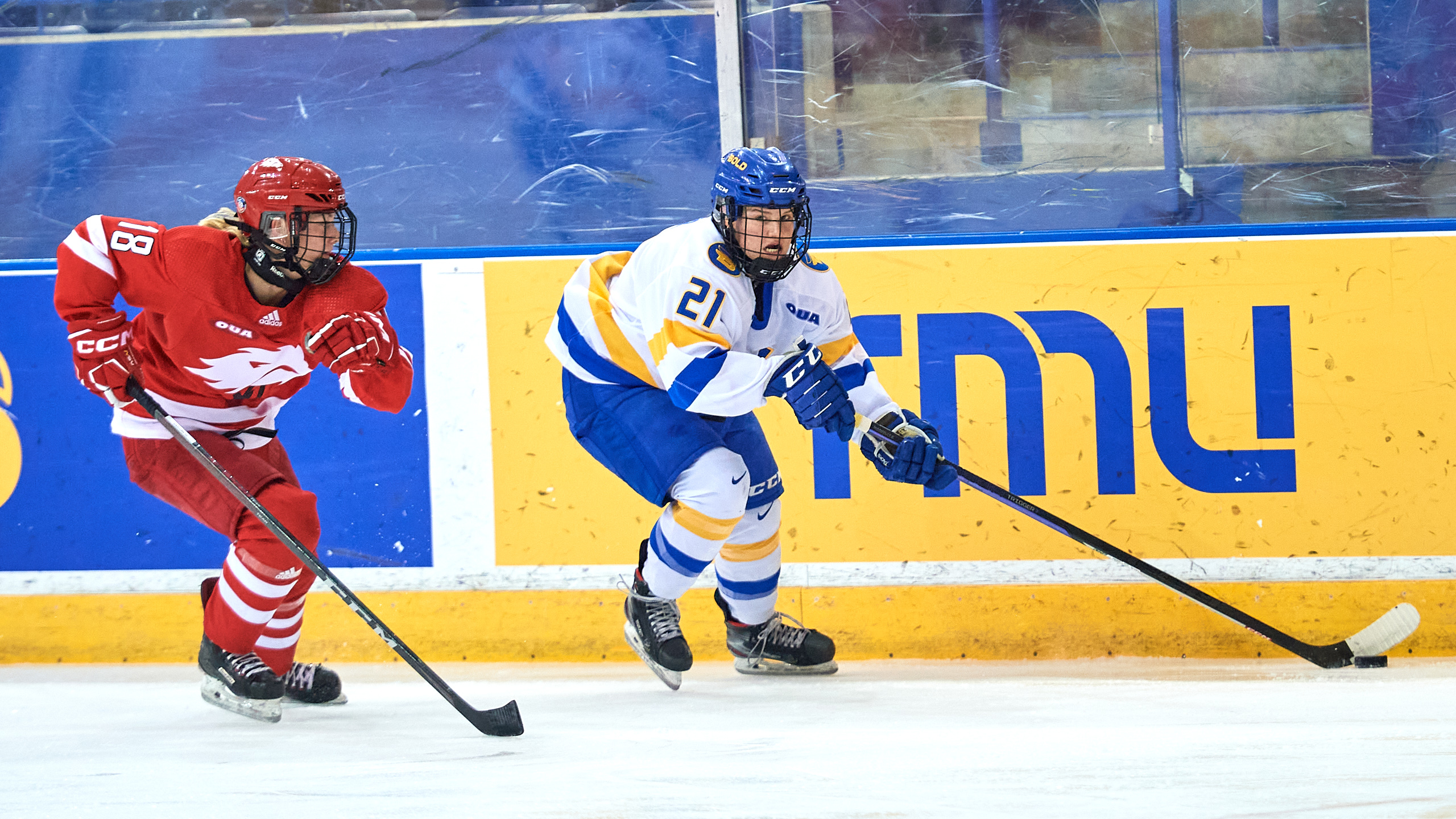 TMU women's hockey player Emily Baxter skates with the puck while being chased by a York Lions defender