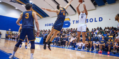 TMU Bold men's basketball player Aaron Rhooms shoots over a Queen's player