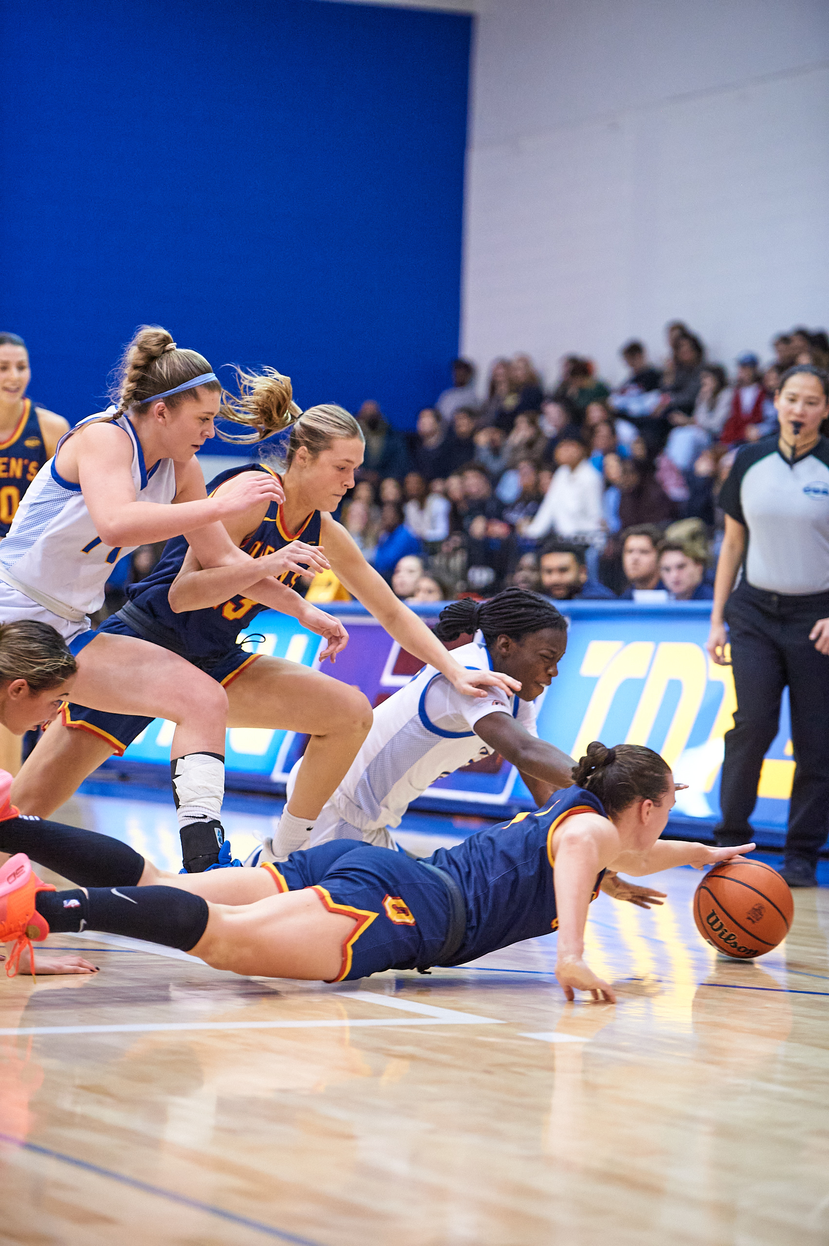 Players from TMU and Queen's dive for the loose ball